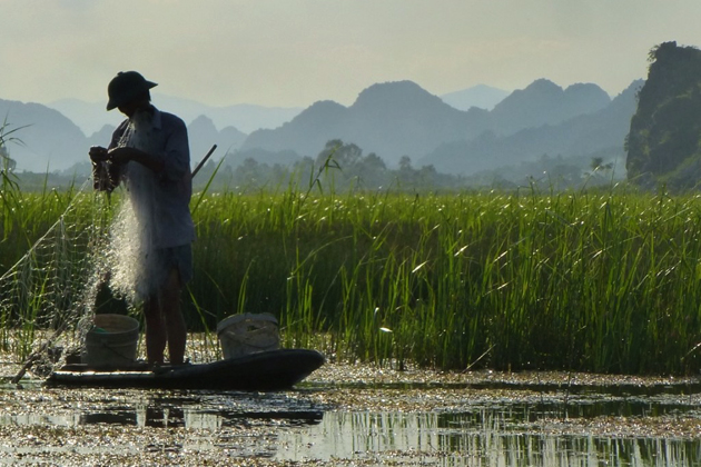 Local people fishing on his boat in Van Long Nature Reserve