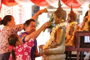 The grandma guide her child how to bath the Buddha in Bunpimay, Laos